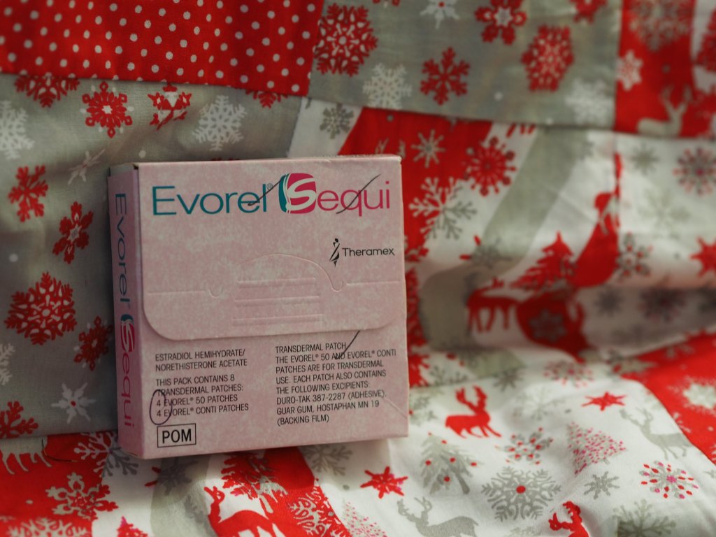 Pink box of Hormone Replacement Therapy patches  with the background of a festive quilt. 
